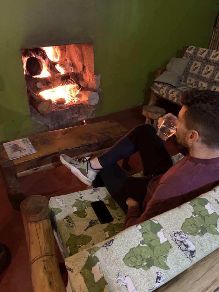 a man drinking gin tonic in bwindi uganda in front of fireplace
